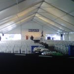Image of a tent with white chairs set up for a conference